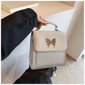 Gros plan d'un sac à main gris en similicuir avec un fermoir papillon argenté élégant