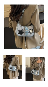 Détail du sac hobo avec bordure en cuir bleu, écussons étoiles et chaîne décorative