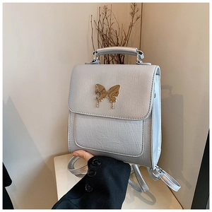 Détail du sac à dos en cuir bleu clair avec une boucle élégante en forme de papillon doré