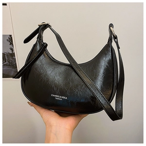 Détail du sac croissant noir brillant avec ferrures argentées et bandoulière réglable