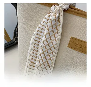 Close-up of beige lychee leather tote bag with fashion scarf and leather nameplate detail