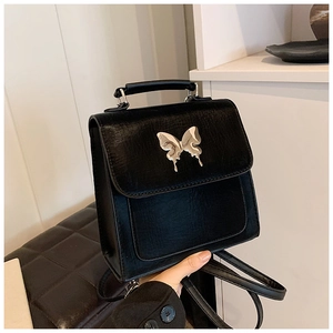 Détail du sac à dos en cuir PU noir avec papillon en métal argenté et texture fine