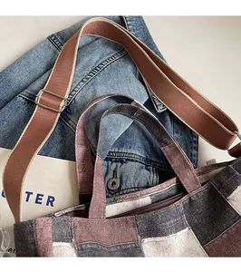Detail of color-block canvas tote bag with adjustable brown strap on denim jacket