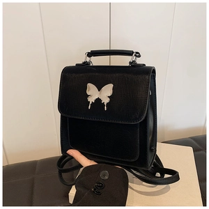 Détail d'un sac à dos en cuir noir avec boucle décorative papillon argentée liquide