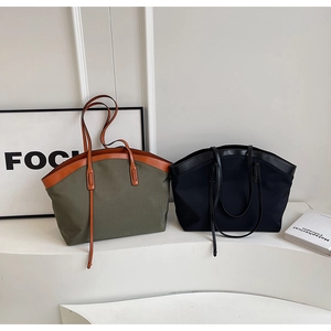Detail of large nylon tote bags in olive green and black with leather handle accents
