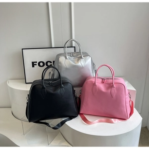 Three large tote bags in black, silver, and pink displayed on a white tiered platform