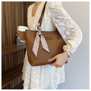 Detail of a brown leather tote bag with lychee texture and a stylish patterned scarf