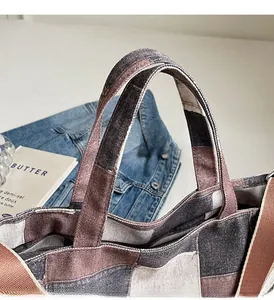 Detail of stitched wide handles and patchwork design on the canvas tote bag for durability