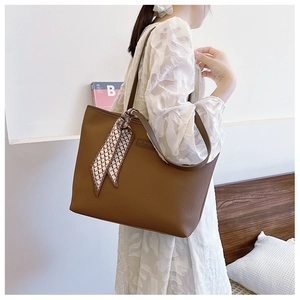 Detail of dark brown pebble leather tote bag with elegant silk scarf on handle