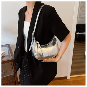 Détail d'un sac demi-lune argenté métallisé avec bandoulière porté par un mannequin