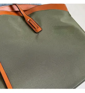Detail of olive green woven fabric and brown leather trim on a large tote bag