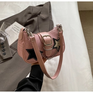 Détail du sac tressé rose avec écusson étoile et bandoulière en chaîne métallique