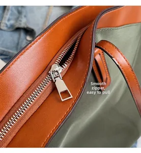 Detailed shot of olive tote bag featuring smooth silver zipper and brown leather trim