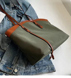 Detail view of khaki Oxford tote bag with brown leather straps on denim jacket background