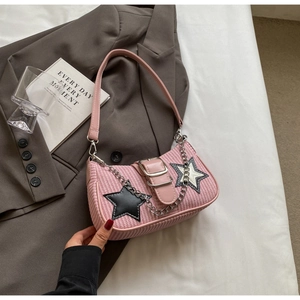 Détail du sac à main tissé rose avec écussons étoiles noirs et blancs et chaîne argent
