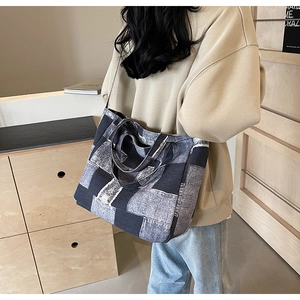 Detailed view of frayed patchwork denim tote bag worn by model in a cozy setting