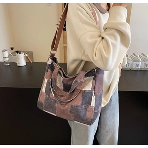Detail of color-block denim tote bag with brown adjustable strap in a cafe setting