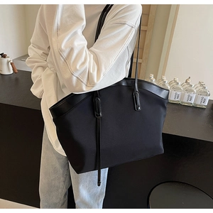 Close-up of minimalist black tote bag with leather straps and metallic accents