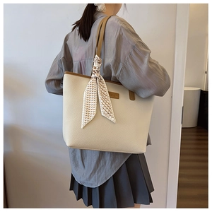Detail view of large cream tote bag with brown trim and checkerboard silk scarf wrap