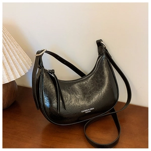 Détail du sac croissant noir montrant la texture cuir ciré et la boucle argentée