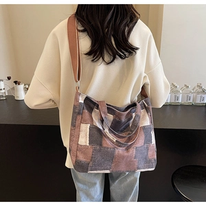 Detailed patchwork denim tote bag with wide straps shown on a model in a cafe setting