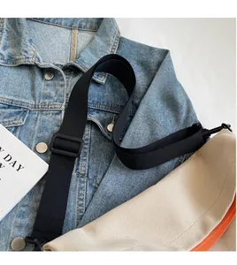 Detail of adjustable wide nylon shoulder strap and orange zipper on canvas tote bag