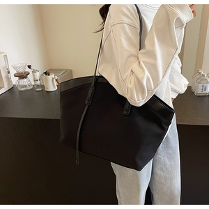 Macro detail of black nylon tote bag with leather straps and minimalist buckle design