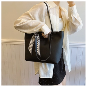 Detail of black pebbled leather tote bag with stylish black and white silk scarf handle