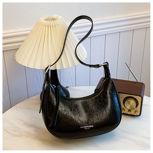 Détail du sac demi-lune noir en similicuir plissé avec logo et fine bandoulière élégante