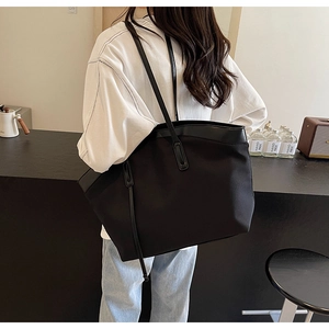 Detail of a large black Oxford tote bag showing the high-density fabric and leather trim