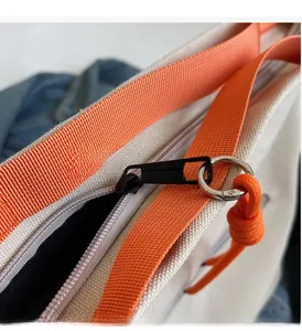Close-up of smooth metal zipper with orange cord detail on canvas tote bag
