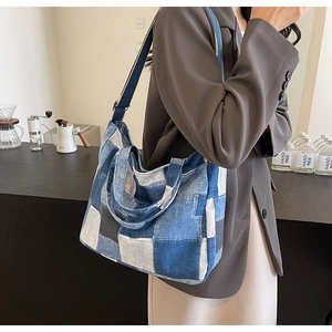 Detail shot of the large denim patchwork tote bag showing blue fabric panels and wide strap