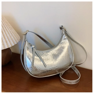 Vue détaillée du sac demi-lune argenté avec texture métallique plissée sur bois