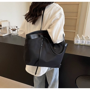 Detail view of durable black nylon tote bag with leather straps on a modern bar counter