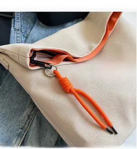 Close-up of smooth black metal zipper with orange knotted puller on canvas tote bag