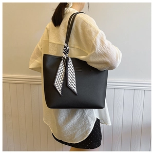 Detail of black pebbled leather tote bag with geometric silk scarf on shoulder