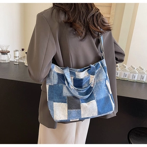 Detail of a large denim patchwork tote bag styled on a model in a cafe setting
