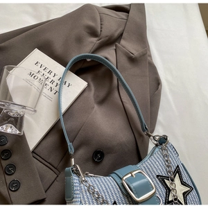Détail du sac bandoulière tissé bleu et blanc avec écusson étoile et chaîne sur veste