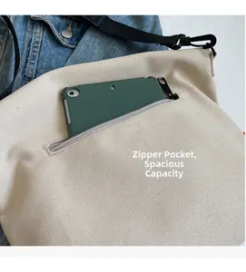 Detail of the front zipper pocket and spacious interior of the cream canvas tote bag