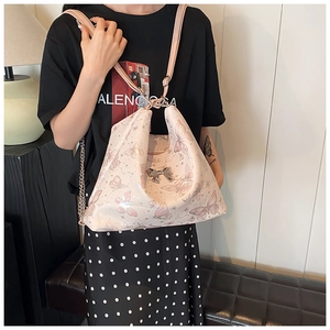 Detail of pink butterfly print tote bag featuring silver bow metal ornament and chain strap