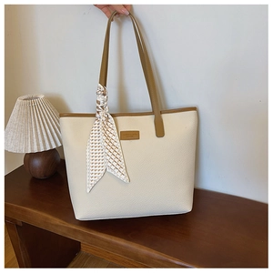 Close-up of cream tote bag featuring lychee texture, brown leather trim, and a silk scarf