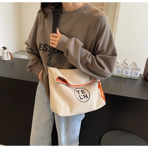 Detail of canvas tote bag showing orange contrast lining and circular logo detail
