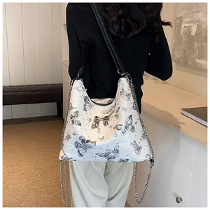 Detail showing white butterfly print tote with metallic bow and silver chain strap