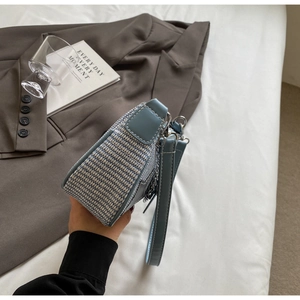 Détail de la texture en cuir bleu et tissu tissé de ce sac à bandoulière élégant