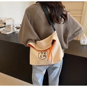 Detail of canvas tote with bright orange lining and black nylon shoulder strap