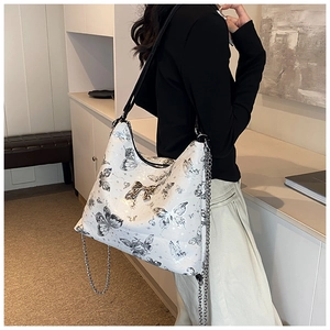 Detail of large white butterfly print tote bag with gold buckle and metal chain strap