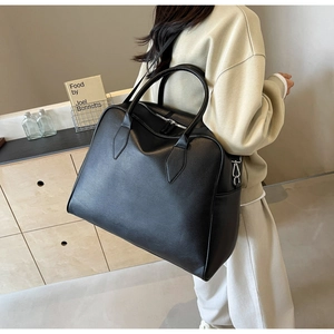 Detail of a black pebbled leather tote bag with sturdy handles and metal side hooks