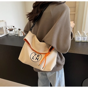 Detail of canvas tote bag showing orange contrast lining and black adjustable strap