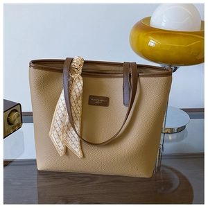 Close-up of khaki tote bag with brown trim and decorative geometric patterned silk scarf