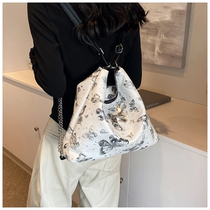 Detail of white tote bag with black butterfly prints and silver metal bow ornament